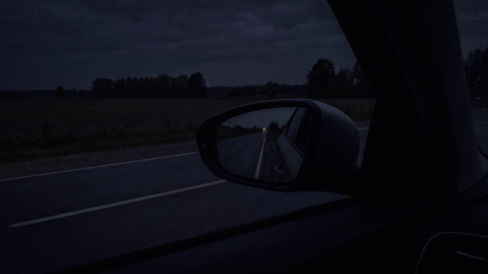 Noću, iz vozačevog sedišta: u levom retrovizoru srebrni šlep sa upaljenim narandžastim svetlom na uzglavlju dolazi i staje iza automobila.
